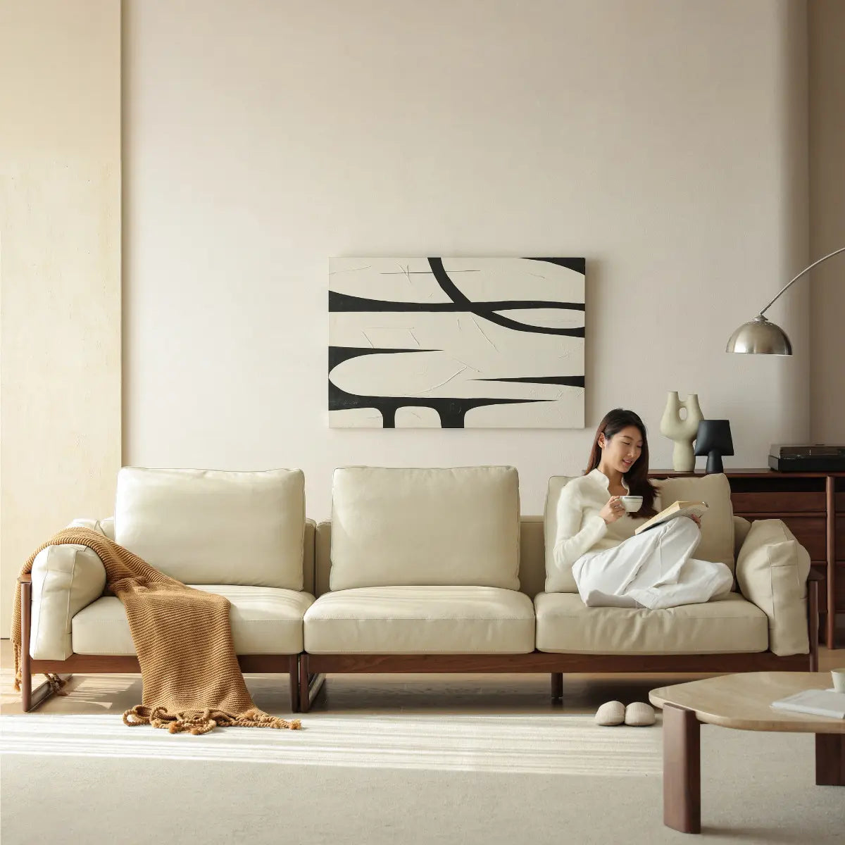 Front view of The Sylvan Reserve solid walnut sofa with cream leather upholstery in a minimalist Japandi living room.