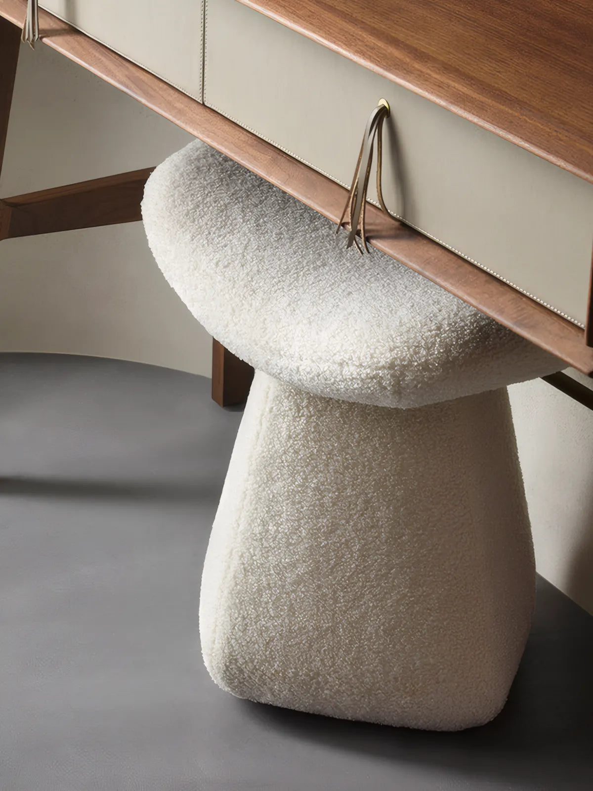 Detail shot of the solid North American Black Walnut legs connecting to the upholstered seat, showcasing the premium wood grain and leather accent strap.

