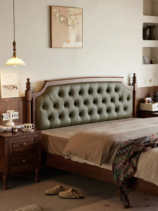 Front view of Kurumi solid walnut bed frame with emerald green tufted leather headboard and turned post legs.
