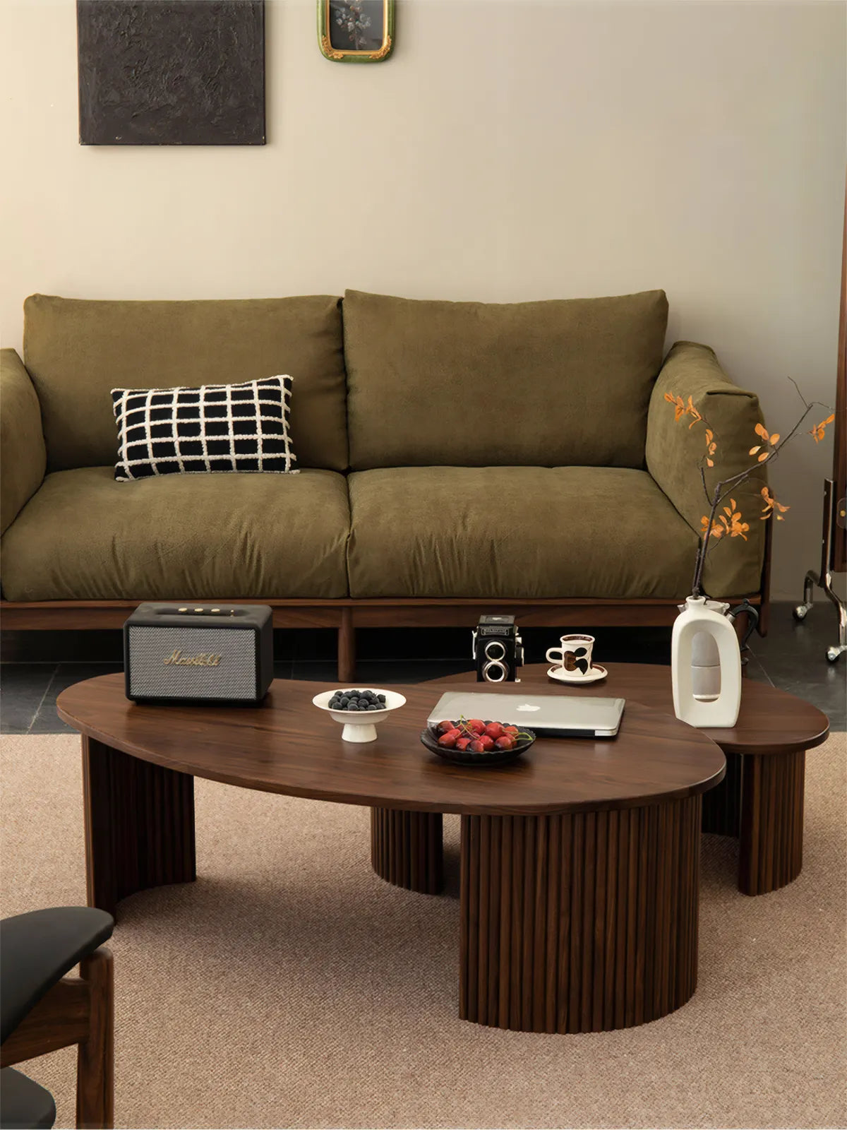 "Kurumi solid walnut nesting coffee table set with fluted legs in a Japandi living room with green sofa."