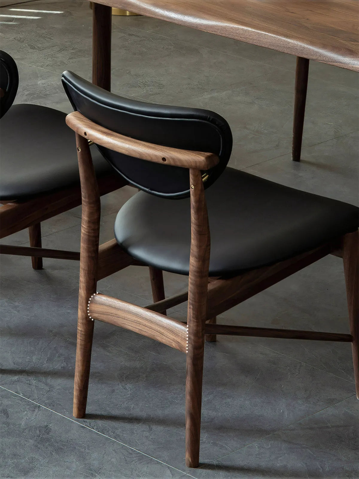 Rear view of the Sylvan dining chair highlighting the steam-bent solid black walnut backrest and brass accent hardware construction.