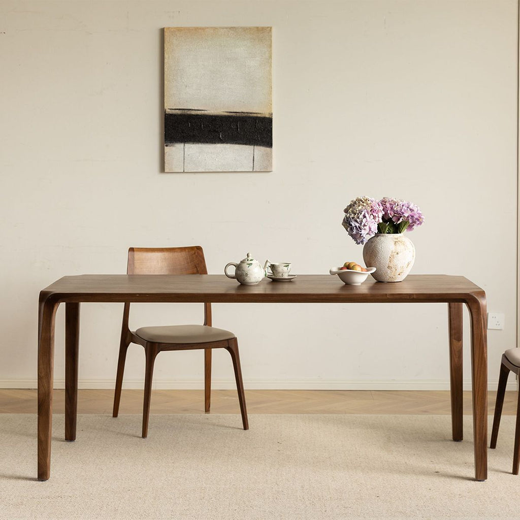 Minimalist solid walnut dining table by WALNUTRY WOOD with curved legs and wooden chairs in a neutral room