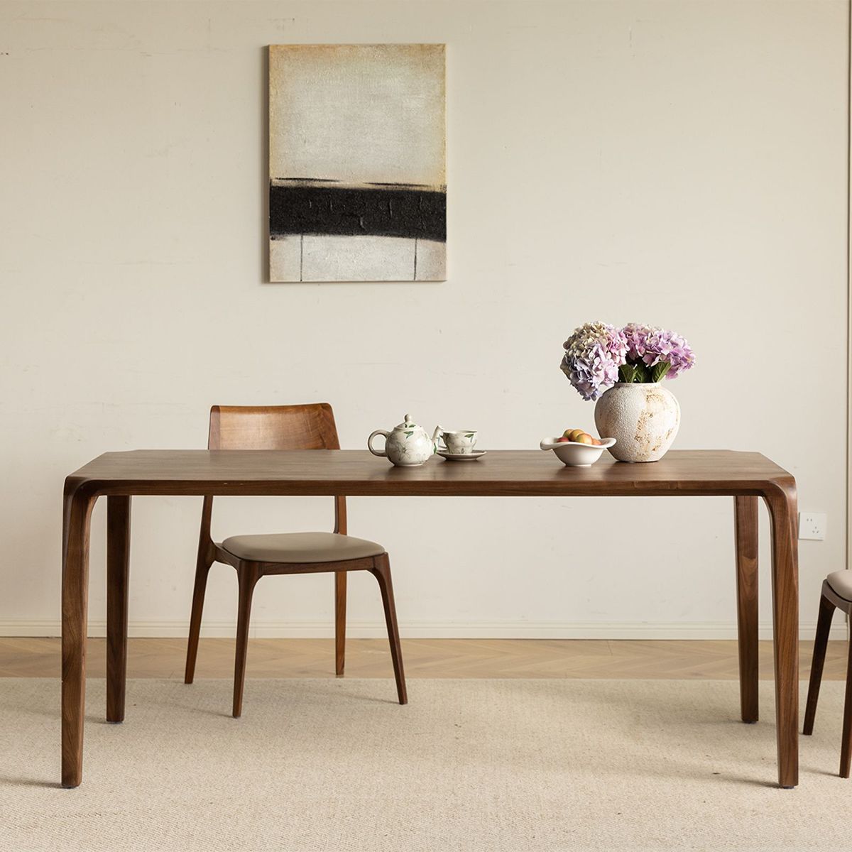 Minimalist solid walnut dining table by WALNUTRY WOOD with curved legs and wooden chairs in a neutral room
