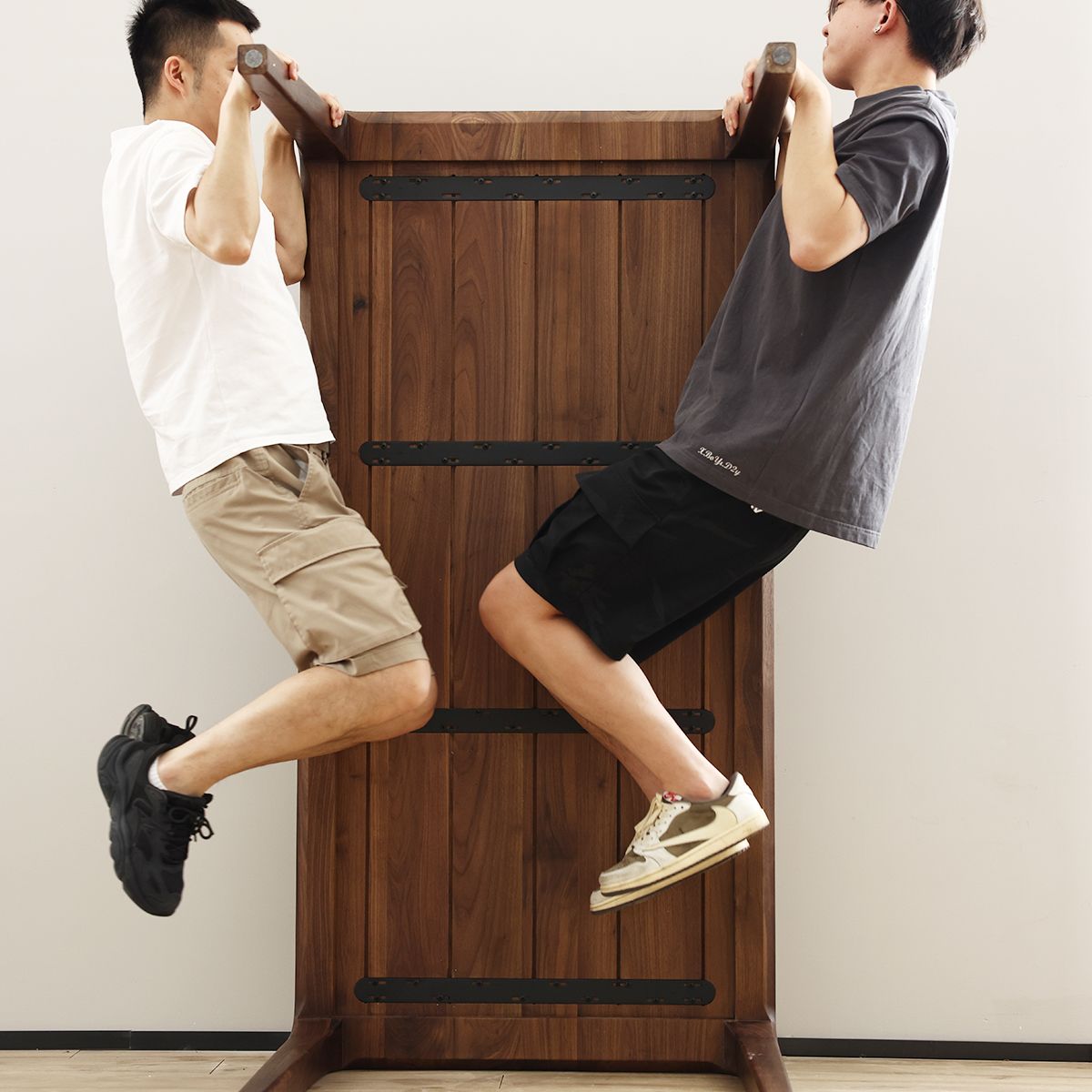 Two men lifting a solid walnut dining table showing sturdy underside with metal supports by WALNUTRY WOOD