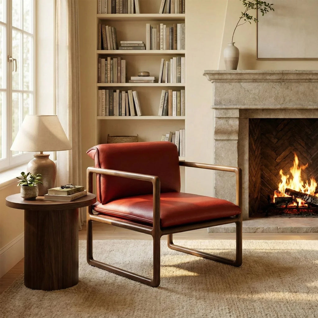 Red leather armchair with walnut sled base beside wooden side table, lamp, fireplace, and bookshelf
