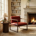 Red leather armchair with walnut sled base beside wooden side table, lamp, fireplace, and bookshelf