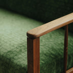 Side view of solid walnut sofa armrest with green patterned upholstery and spindle details