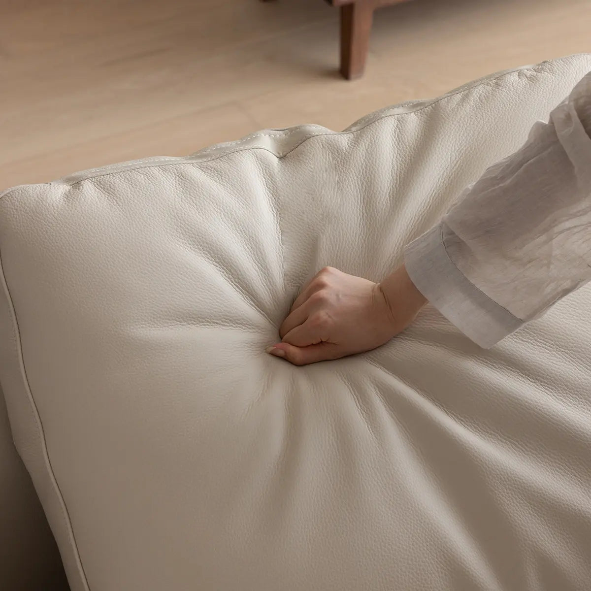 Close up of hand-pressed leather/fabric cushion on solid walnut frame showing softness and wood texture.