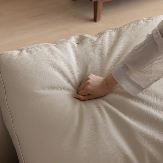 Close up of hand-pressed leather/fabric cushion on solid walnut frame showing softness and wood texture.