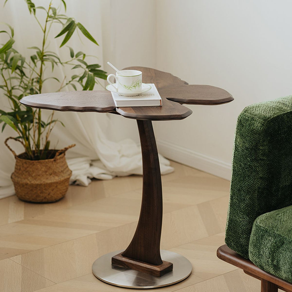 Solid wood end table with carved legs and sculpted top holding a cup and book in a modern living room
