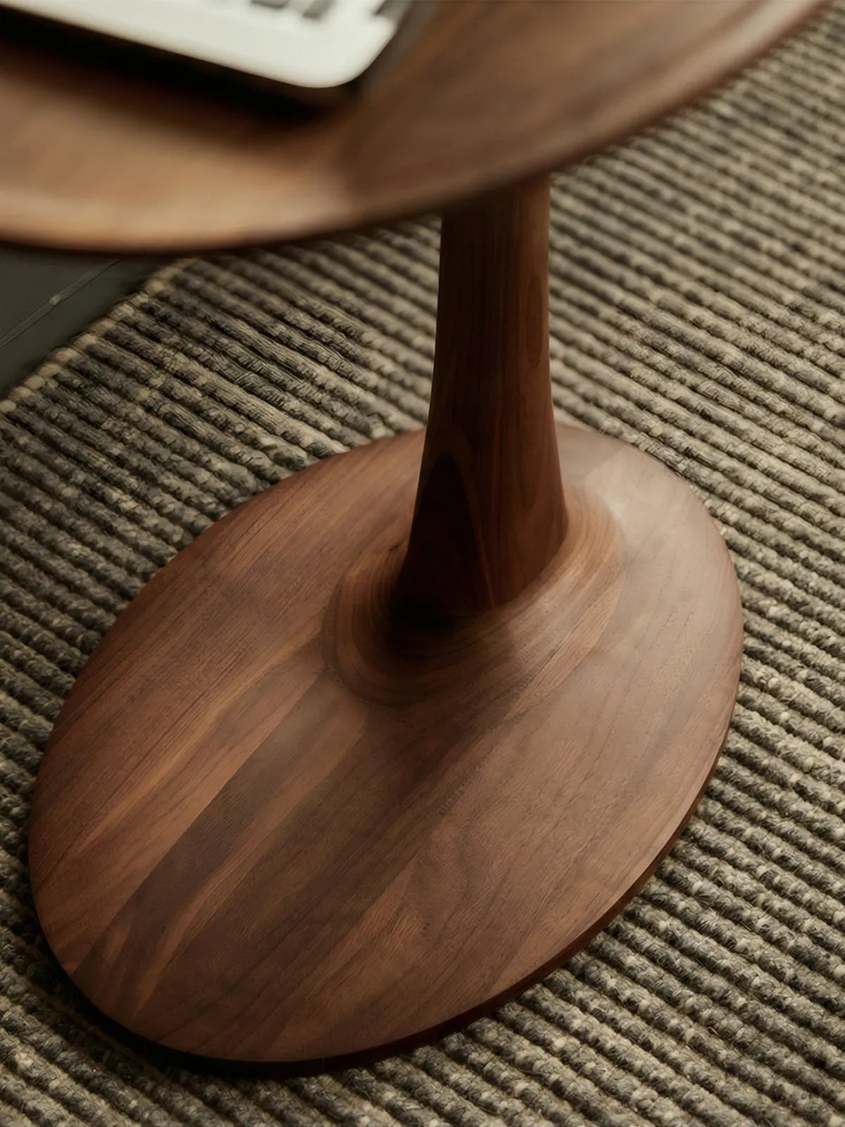 Detail shot of the tapered solid wood pedestal base of The Orbit side table, highlighting the seamless joinery and stable construction.
