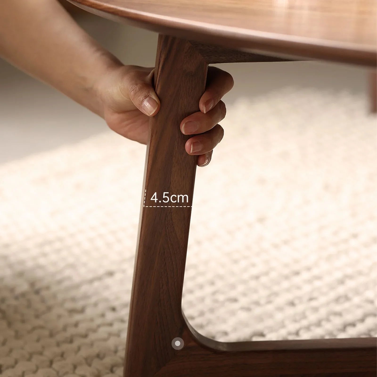 Hand holding solid walnut tapered table leg measuring 4.5cm thickness on woven rug