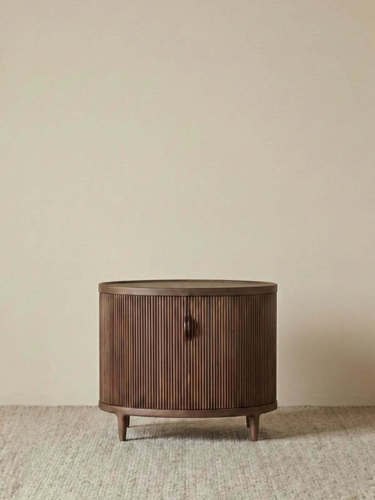 Front view of the Suiseki Oval Nightstand made of North American black walnut, featuring a continuous vertical slat design and tapered legs.