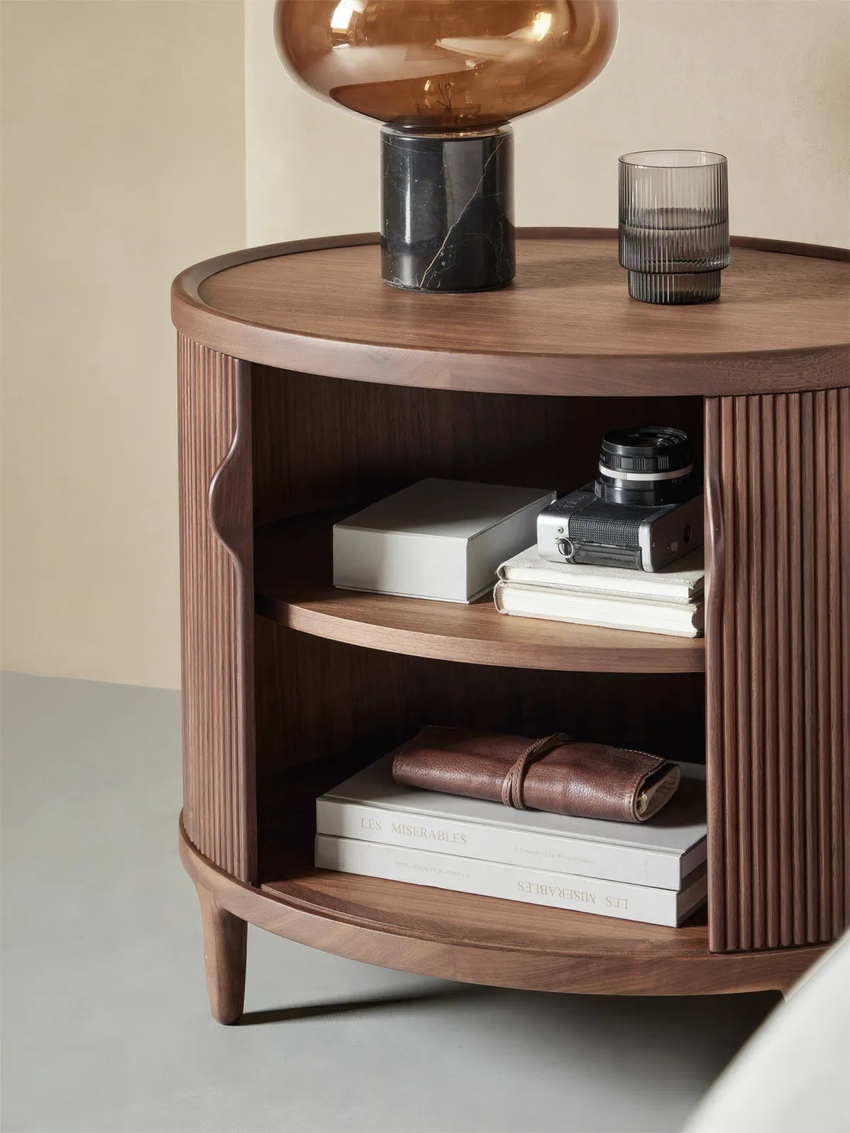 Suiseki Oval Nightstand with door open, revealing a two-tier storage shelf perfect for organizing books and personal items.