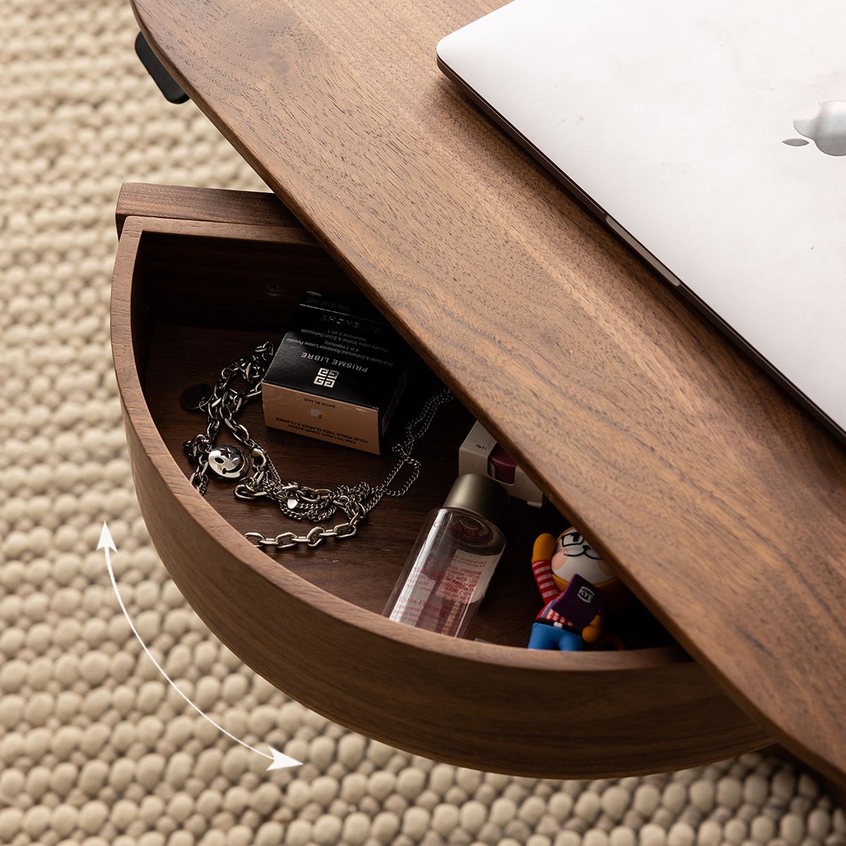 Wooden swivel drawer storage under table with jewelry, perfume, toy, and laptop on textured rug