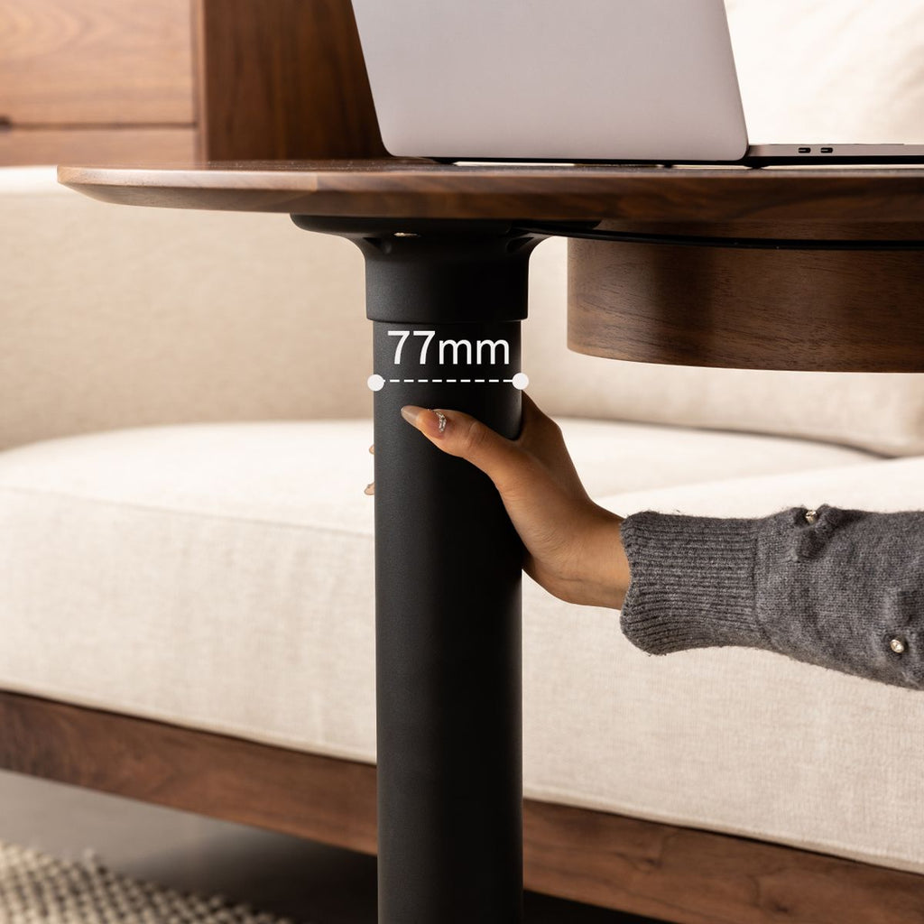 Hand holding a black metal swivel pillar of a wooden table showing 77mm diameter in a modern living room