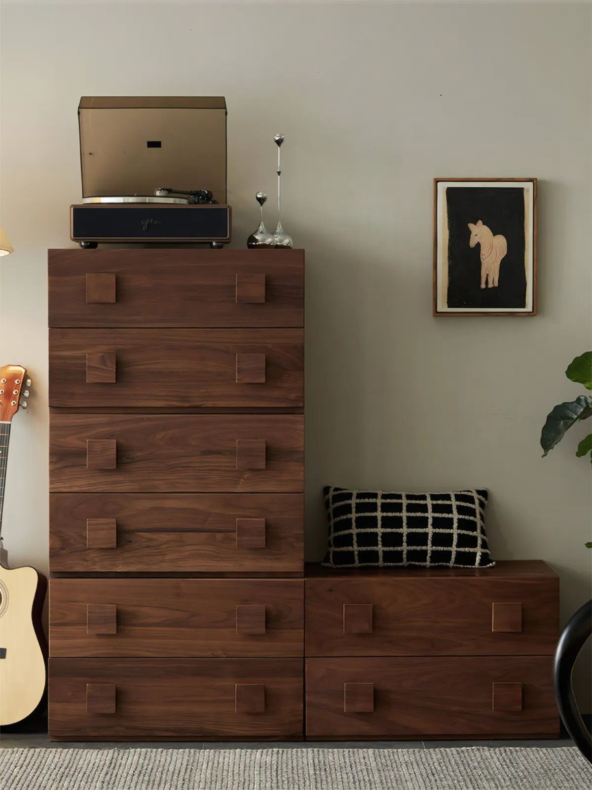 A stack of Walnutry modular drawer units forming a tall dresser in a minimalist bedroom setting with vinyl player on top.