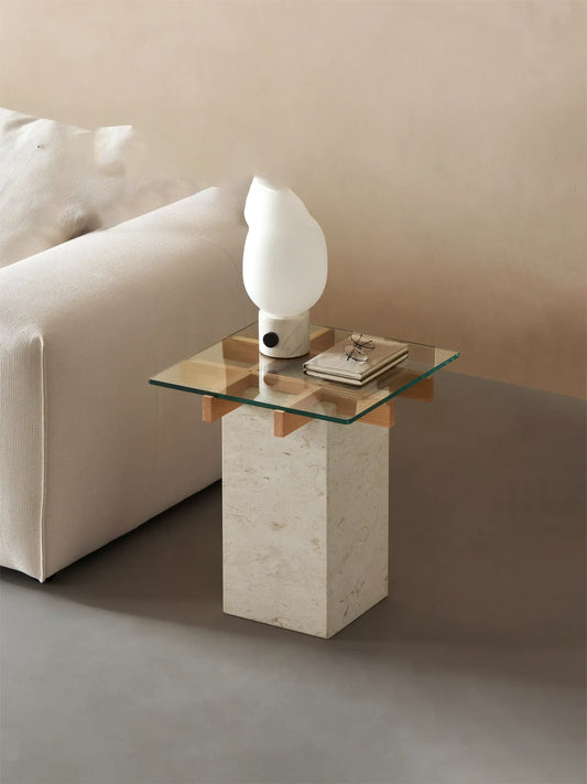 Close up of tempered glass table top resting on walnut joinery and travertine stone column.