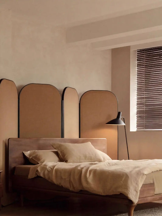 Angled view of The Estate Bed Frame highlighting the tapered legs and smooth solid wood headboard in a modern bedroom setting.