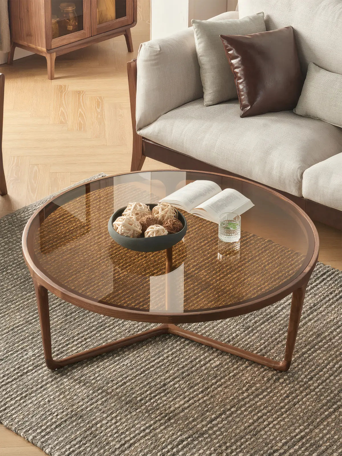 Overhead view of the two round nesting tables, demonstrating how the smaller walnut table tucks neatly under the larger amber glass table to save floor space.