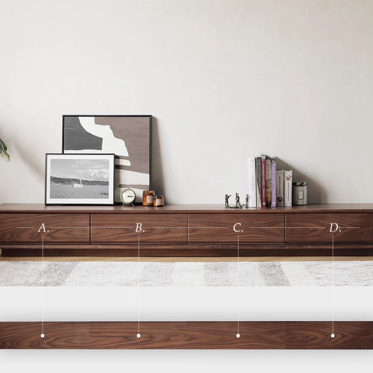 Ultra low wooden TV cabinet with art frames, clock, candles, books, and small figurines on top