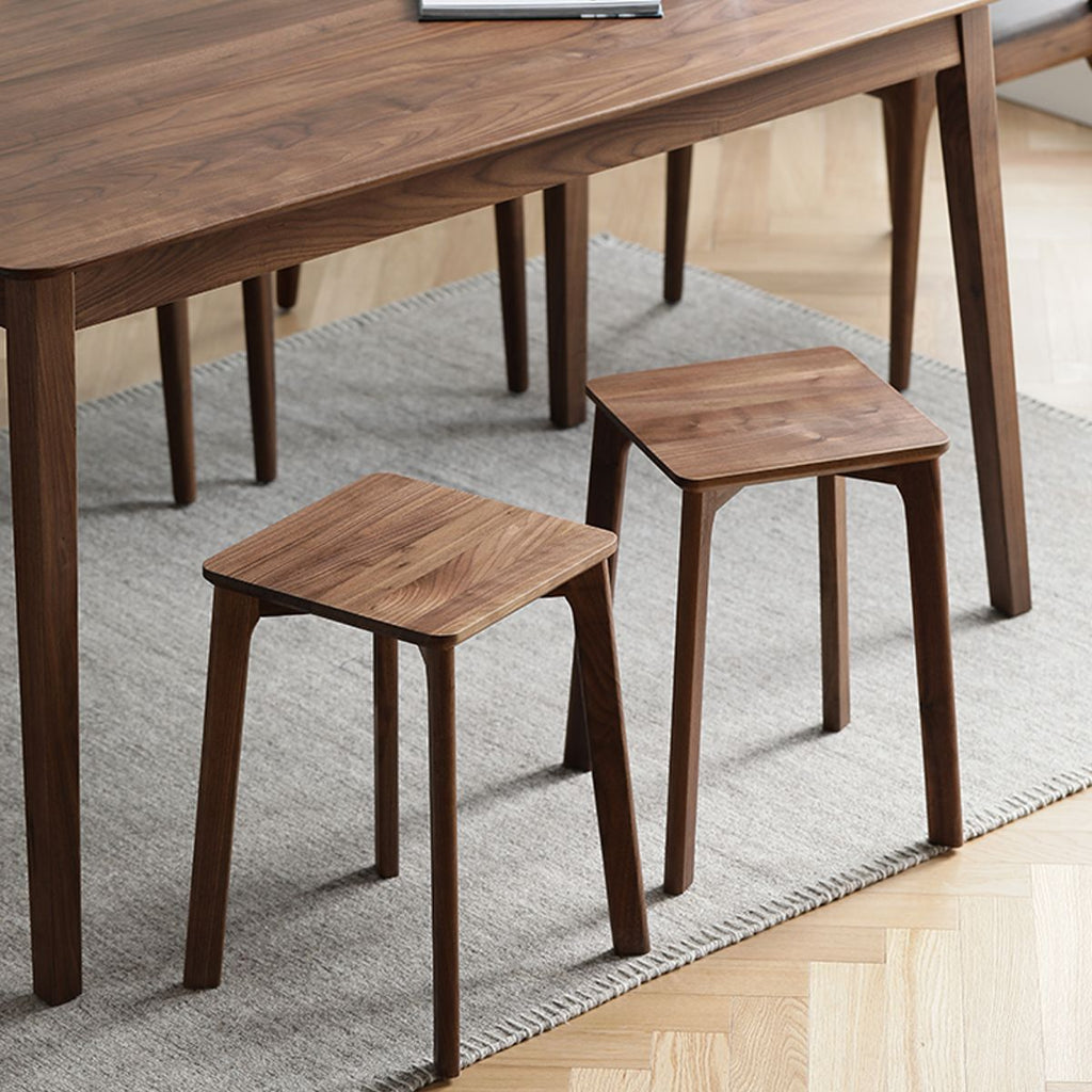 Two versatile wooden stools used as side tables on a gray rug under a wooden dining table