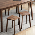 Two versatile wooden stools used as side tables on a gray rug under a wooden dining table