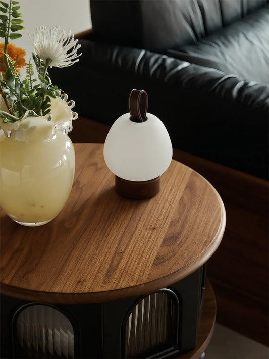 Close-up of solid black walnut grain on round drum table top with mushroom lamp and flowers.