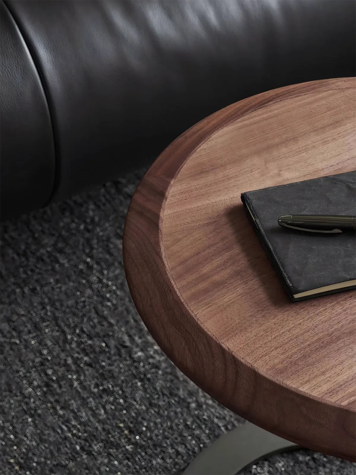 Top-down view of the circular walnut side table surface with a notebook and pen, highlighting the smooth finish and natural wood texture.