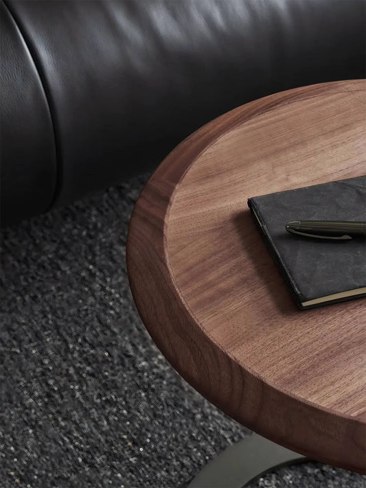 Top-down view of the circular walnut side table surface with a notebook and pen, highlighting the smooth finish and natural wood texture.