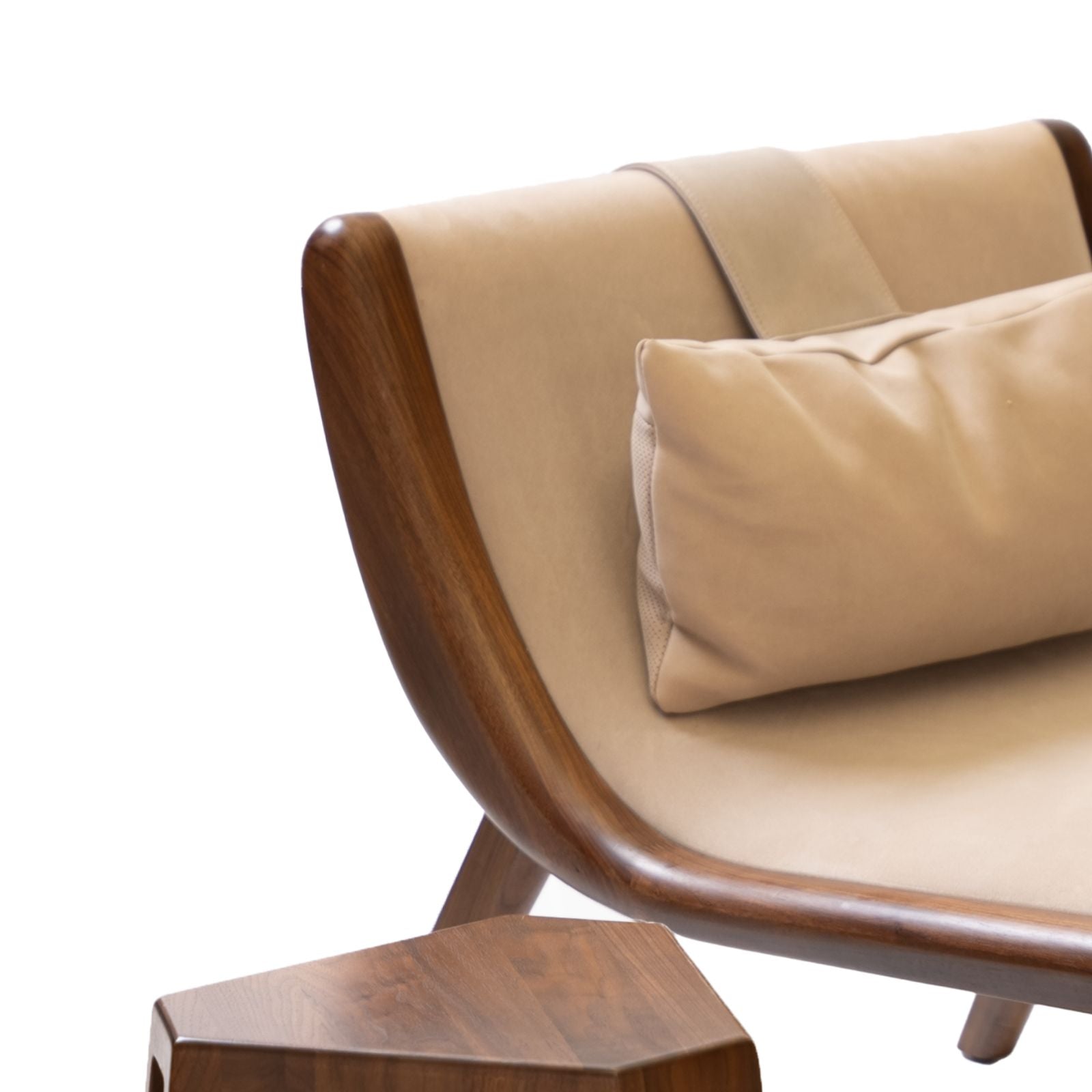 Close-up of sculptural chaise lounge with beige cushion and solid walnut frame, next to walnut side table