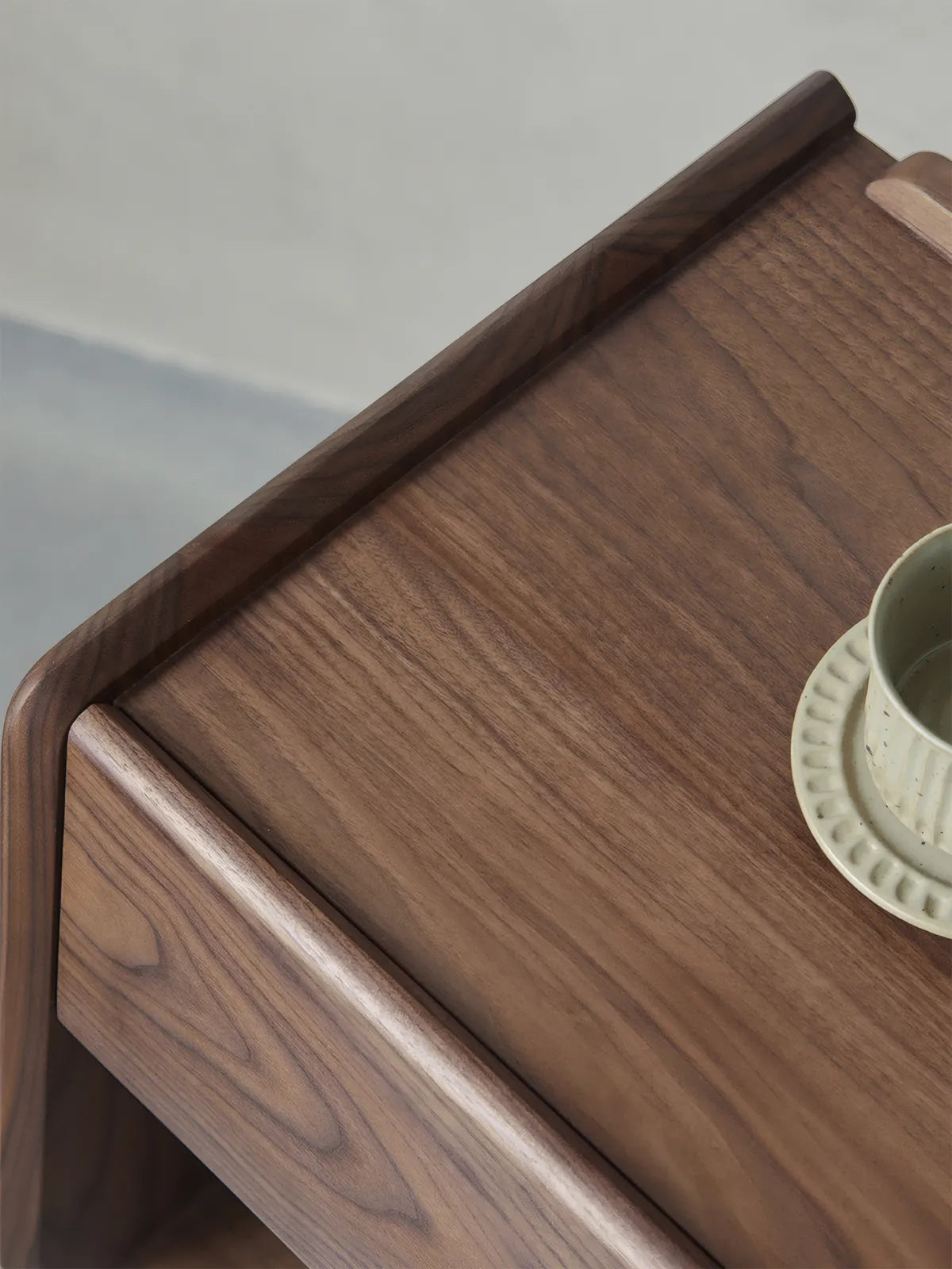 Detail shot of nightstand top surface showing natural black walnut grain patterns and smooth rounded edges.