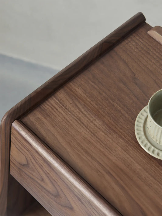 Detail shot of nightstand top surface showing natural black walnut grain patterns and smooth rounded edges.