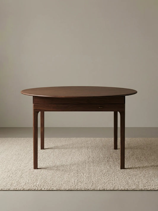 Front studio view of the walnut extendable dining table on a neutral textured rug.