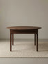 Front studio view of the walnut extendable dining table on a neutral textured rug.
