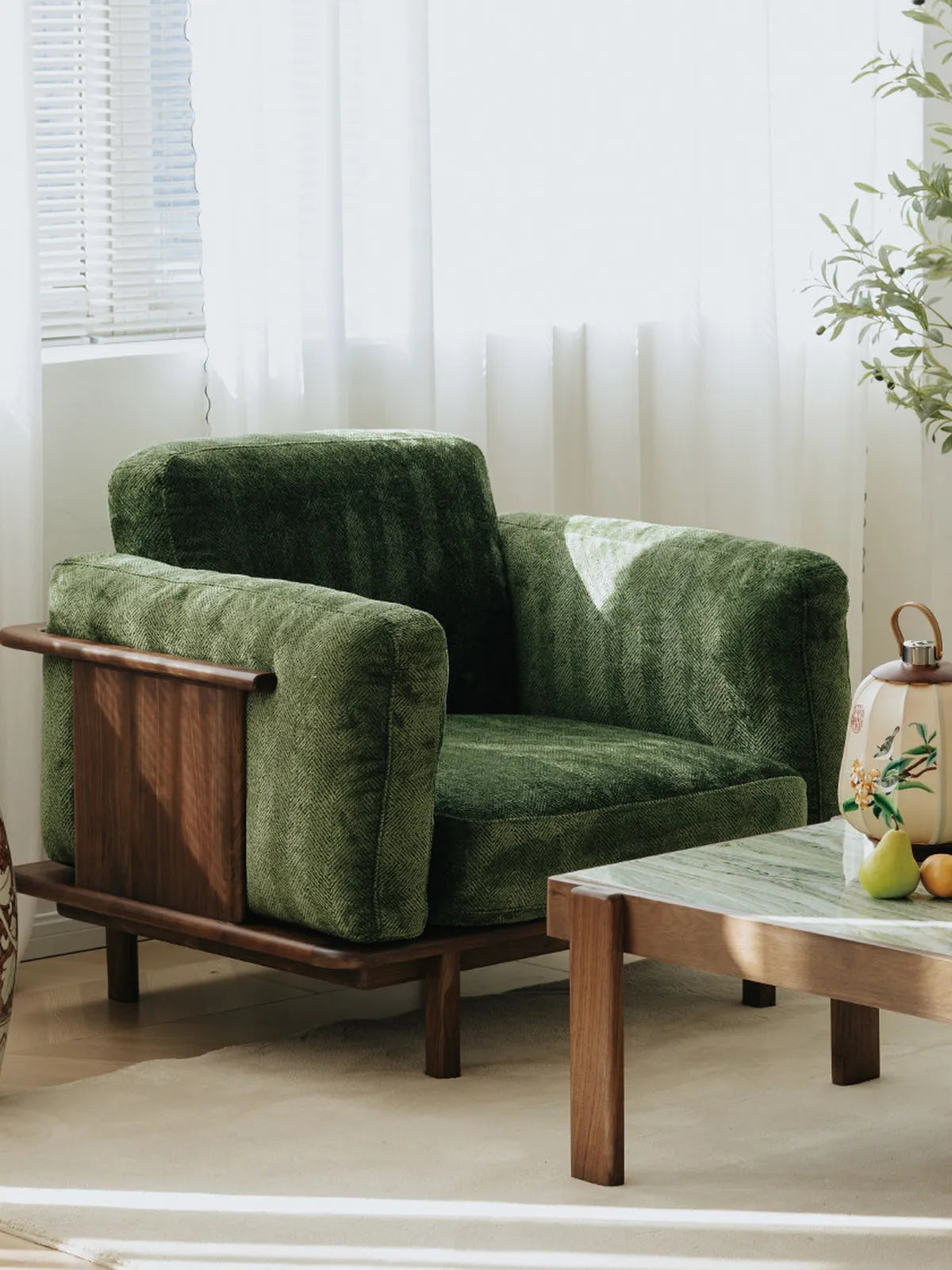 Alden Ridge armchair in green velvet with solid walnut side panel and base, shown beside a walnut coffee table