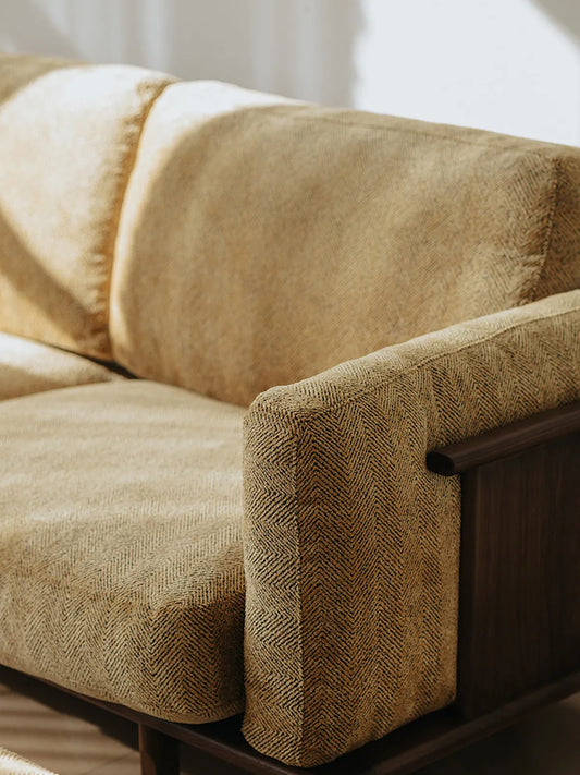 Close-up of Alden Ridge sofa arm in wheat herringbone fabric showing padded armrest and walnut frame edge