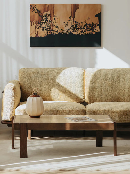 Alden Ridge sofa in wheat fabric from the side, styled with a walnut coffee table and ceramic lamp in a sunlit room