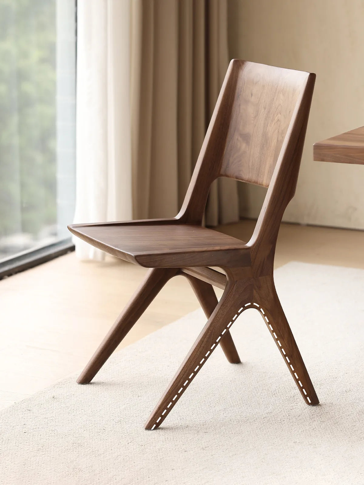 Side profile of the Arlen Dining Chair highlighting splayed legs and backrest curve near a window.