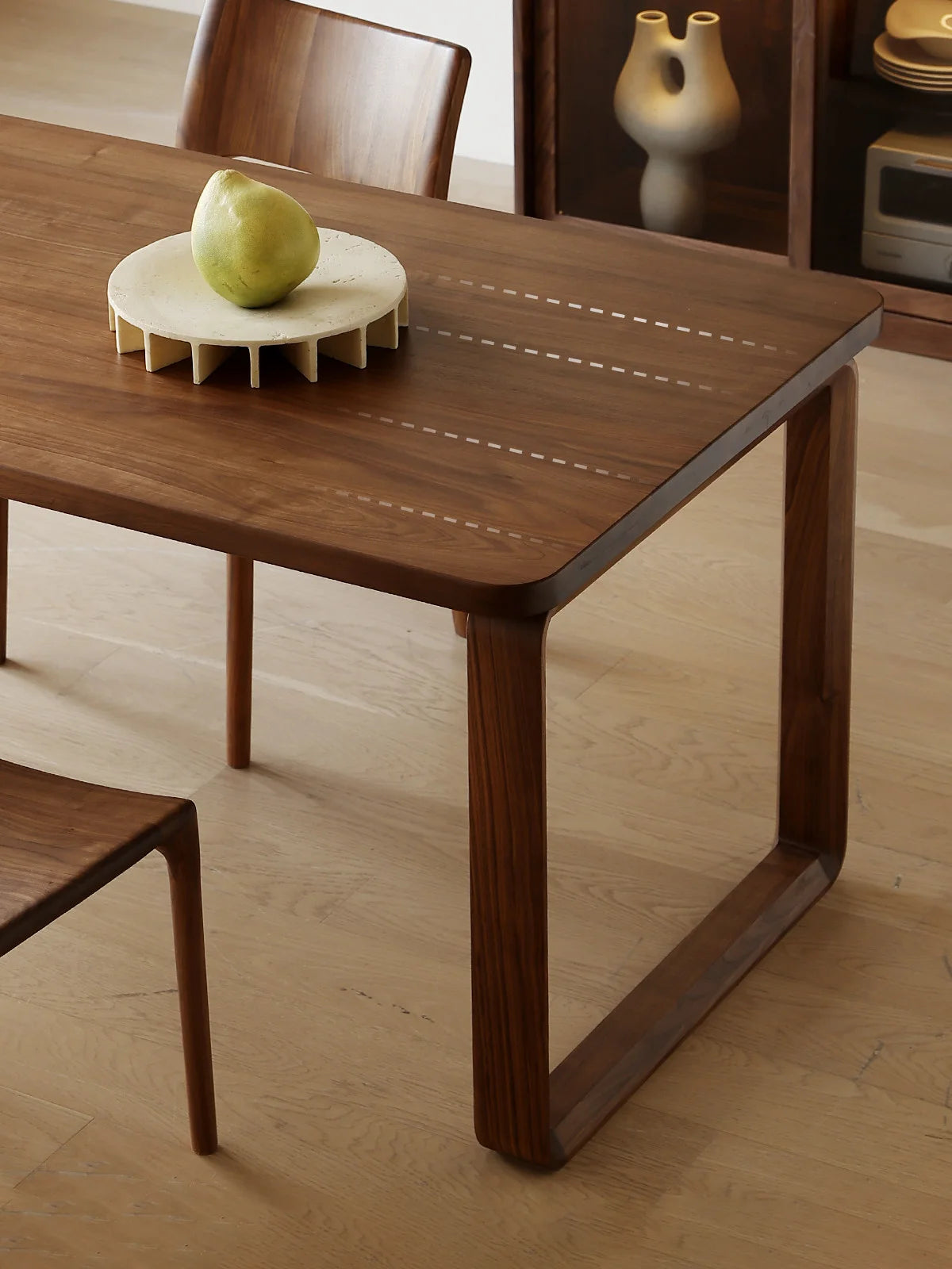 Corner detail of the Auren dark walnut dining table highlighting the spacious seating area and clean leg placement.
