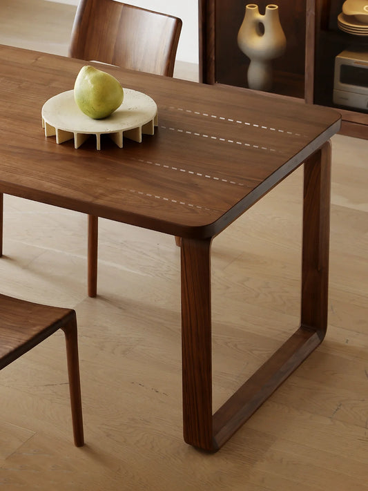 Corner detail of the Auren dark walnut dining table highlighting the spacious seating area and clean leg placement.