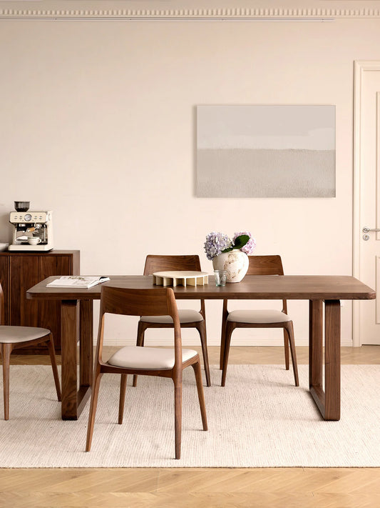 The Auren mid century modern style dining table in solid American walnut styled in a calm dining room setting.