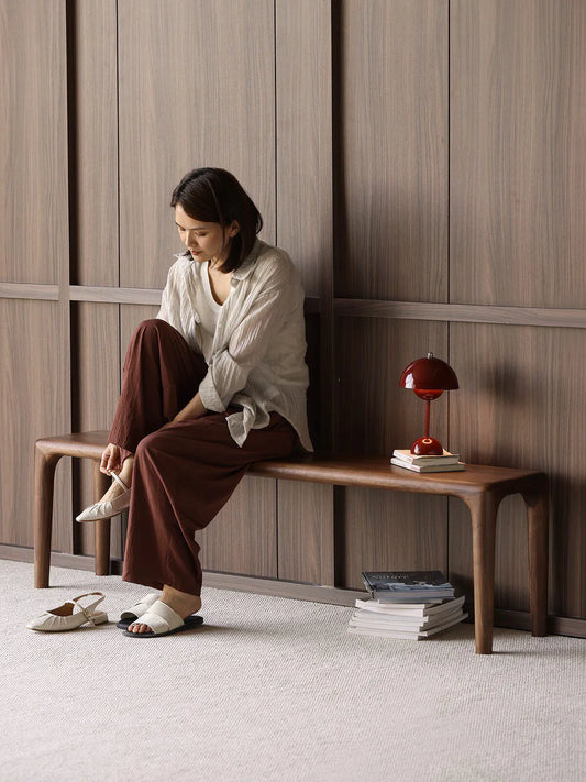 Auren Walnut Bench styled as dining seating in a modern interior with walnut chairs and table, emphasizing its long, elegant proportions.