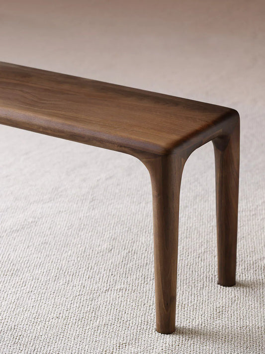 Auren Walnut Bench used as bedroom seating, placed beside the bed with an open book to highlight its warm walnut finish and everyday functionality.