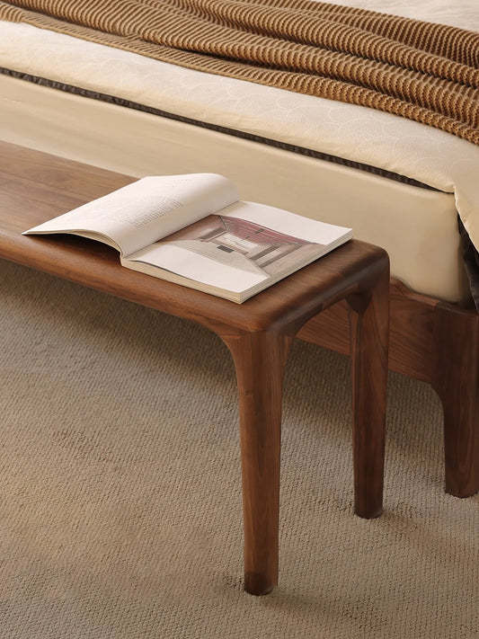 Detailed corner view of the Auren Walnut Bench showing softly rounded edges, sculpted legs, and the natural walnut wood texture.