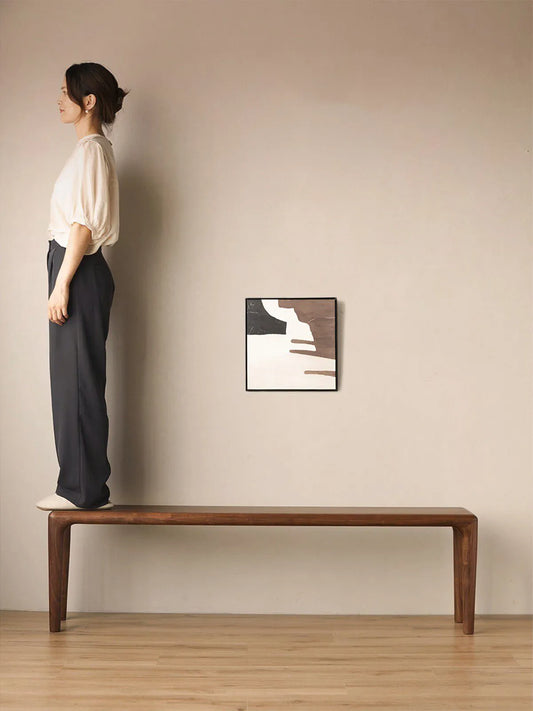A woman standing on the Auren Walnut Bench to demonstrate strength, stability, and durable solid wood construction.