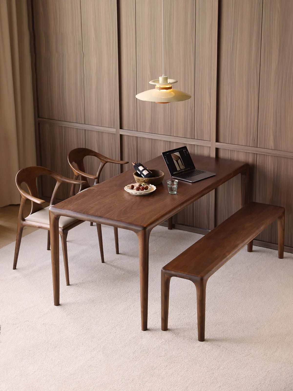 Auren Walnut Bench paired with a solid walnut dining table in a modern dining room, showing its clean lines and sculptural silhouette.