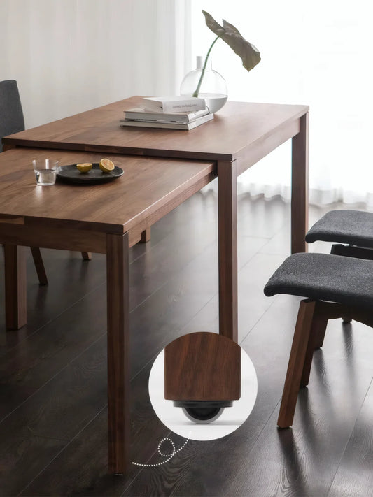 Close view of the walnut extendable dining table with the lower sliding extension pulled out and concealed caster detail shown
