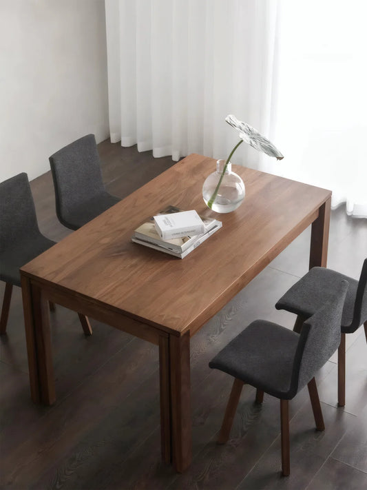 Top angled view of the walnut extendable dining table in its closed position with four dining chairs