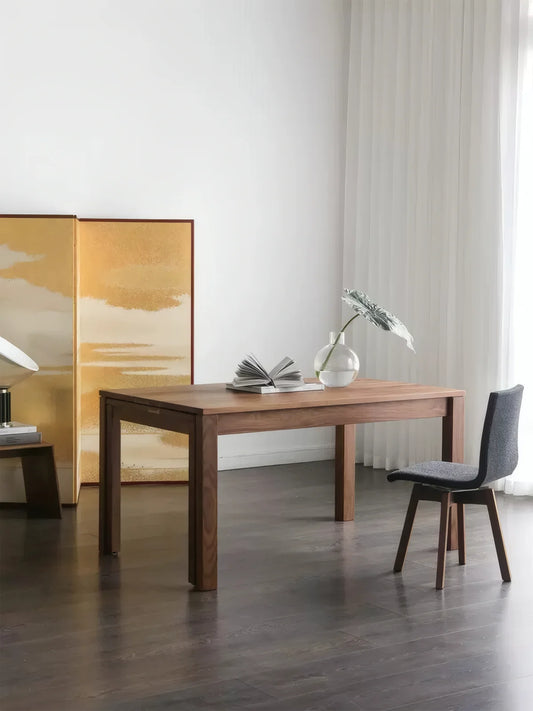 Solid walnut sliding extendable dining table shown partially closed in a bright dining room with one upholstered chair
